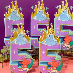 May include: A set of five purple and blue foam numbers decorated with Disney princesses. The numbers are 1, 5, and 5. Cinderella is featured on the 1s and the 5s feature Ariel the mermaid.
