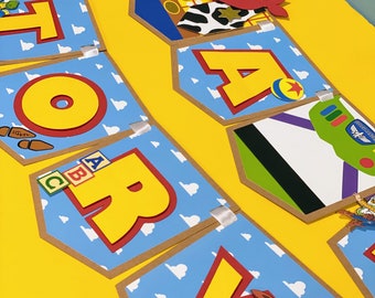 May include: A blue and brown banner with the word "STORY" spelled out in yellow letters. Each letter has a different character from the Toy Story movie, including Woody, Buzz Lightyear, and Jessie. The banner is decorated with white clouds.