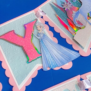 Może przedstawiać: Baner o tematyce księżniczki, z jasnoniebieskim tłem i r&oacute;żowymi, falistymi krawędziami. Baner zawiera r&oacute;żową literę "Y" z brokatem i ilustrację księżniczki w niebieskiej sukni. Dodatkowe elementy to niebieski koń i zamek.