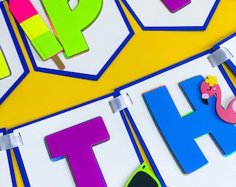 Op de afbeelding: Een kleurrijke banner met het woord "HAPPY" in grote, levendige letters. De letters zijn in paars, groen en blauw, met zomerse versieringen zoals een zon, een ijsje, een zonnebril en een flamingo. De achtergrond is geel.