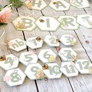 May include: Winnie the Pooh themed birthday party decorations with green and yellow honeycomb shaped paper cutouts. The cutouts feature Winnie the Pooh characters, bees, and the words "Happy Birthday".