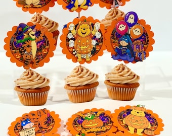 Può includere: Una collezione di decorazioni rotonde per cupcake con bordi smerlati, caratterizzate da illustrazioni colorate di personaggi dei cartoni animati in costume di Halloween, tra cui un gufo, un coniglio e un orso, accanto a tre cupcake con glassa beige.