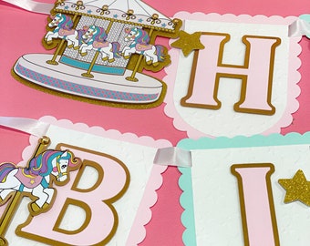 May include: A pink and white banner with the letters "H", "B", and "I" in gold letters with a pink background. Each letter has a gold star on the top right corner. The banner is decorated with a white background with a pattern of small stars. The banner is attached to a pink ribbon.