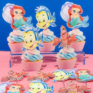 May include: A set of cupcake toppers featuring characters from The Little Mermaid. The toppers include Ariel, Flounder, and Sebastian. The toppers are printed on cardstock and are perfect for adding a touch of Disney magic to your cupcakes.