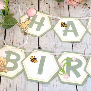 May include: A green and yellow Winnie the Pooh themed banner with the words "Happy Birthday" in green letters. The banner is decorated with bees, flowers, and Winnie the Pooh characters.