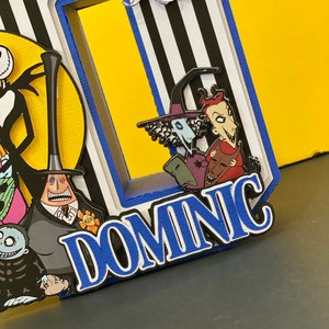 Puede incluir: Un fondo a rayas blanco y negro con un borde azul. El nombre "DOMNIC" est&aacute; escrito en letras blancas con un contorno azul. Hay varios personajes de la pel&iacute;cula "Pesadilla antes de Navidad" en el fondo.