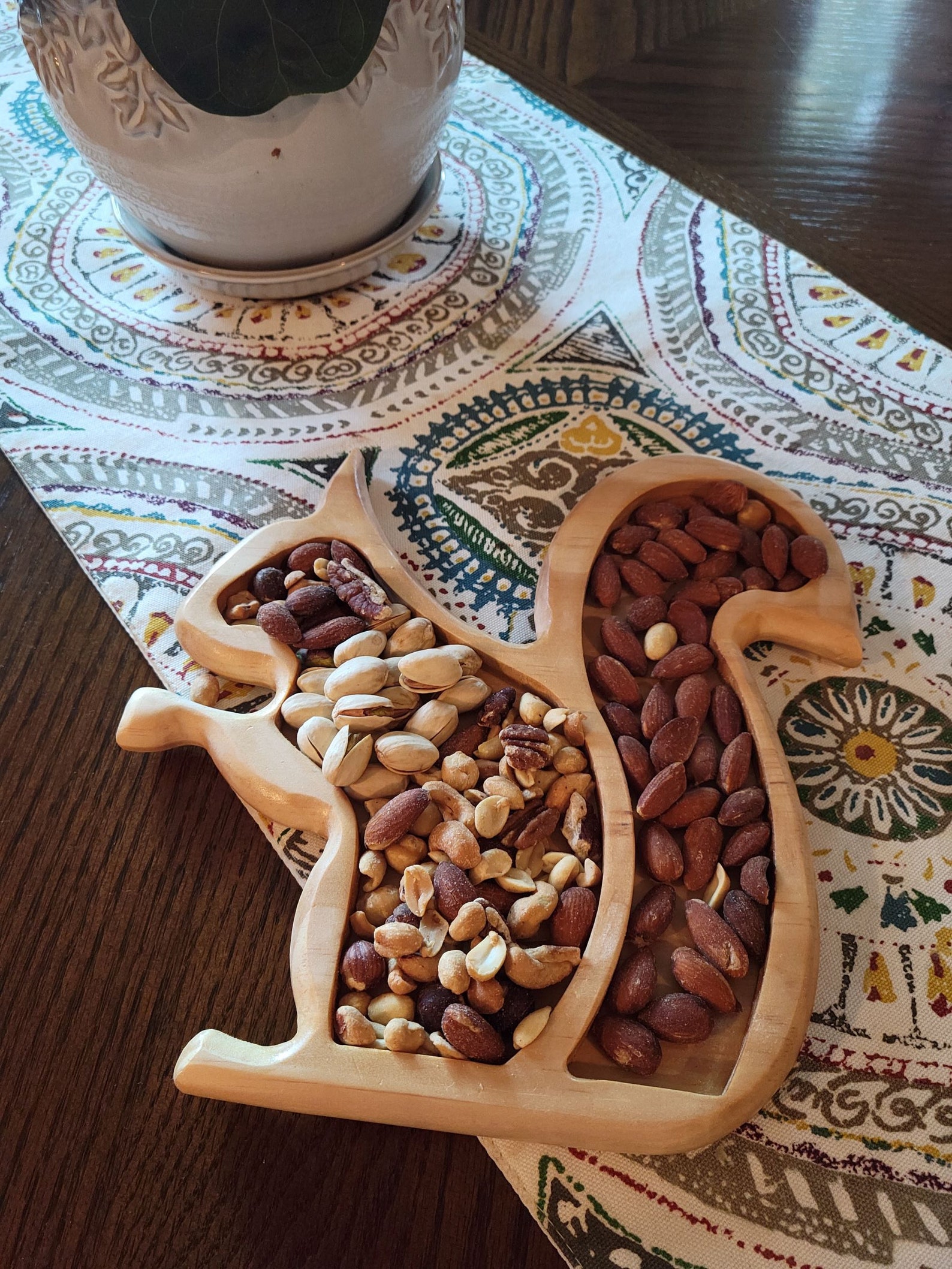 wooden box shaped like a squirrel holding an assortment of nuts