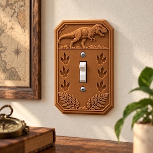 May include: A rectangular brown light switch plate featuring a raised relief of a Tyrannosaurus Rex at the top, six dinosaur footprints flanking a central white toggle switch, and detailed fern leaf patterns at the bottom with two silver screws.