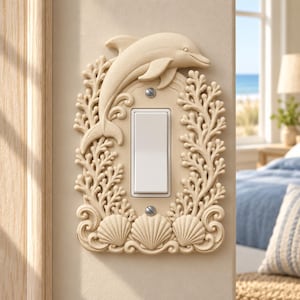 May include: A cream-colored light switch cover featuring a sculpted dolphin at the top, surrounded by intricate coral reef textures and three seashells at the base. The rectangular plate includes a central white rocker switch.