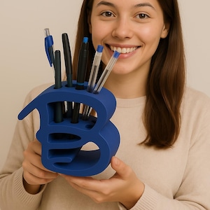 May include: A blue plastic letter B desk organizer with multiple slots for pens and pencils. The organizer is being held by a person.