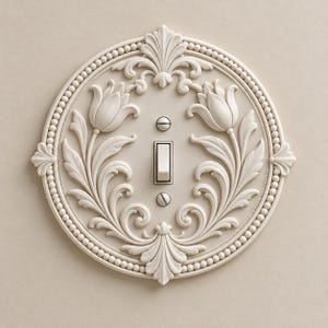 May include: A circular off-white light switch plate featuring an embossed floral design with two tulips and intricate leaf patterns. The border is decorated with a beaded edge, and the center includes a single toggle switch with two screws.