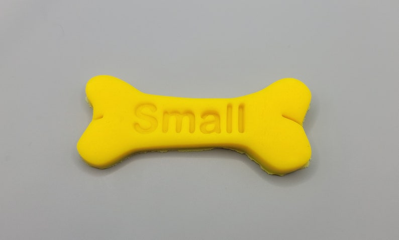 May include: A yellow bone-shaped dog treat with the word "Small" embossed on it.