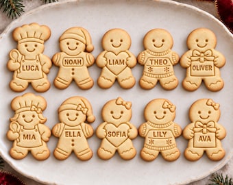 May include: Ten light brown gingerbread cookies arranged in two rows on an oval plate. Each cookie features a unique design, including chef hats, Santa hats, bows, sweaters, and gift boxes, with the names Luca, Noah, Liam, Theo, Oliver, Mia, Ella, Sofia, Lily, and Ava.