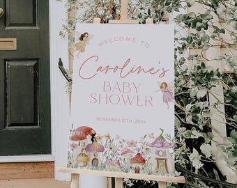 May include: A rectangular welcome sign for a baby shower featuring the text 'WELCOME TO Caroline's BABY SHOWER NOVEMBER 10TH, 20XX'. The design includes illustrations of two winged fairies and several colorful mushroom-shaped houses in a garden.