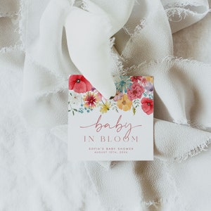 May include: A white card with a floral design and the text "baby in bloom" in pink script. The text below reads "Sofia's Baby Shower August 10th, 20XX".