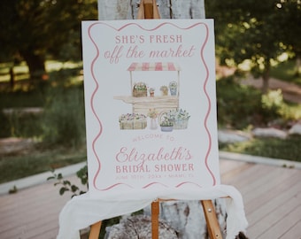 May include: A rectangular white sign with a pink wavy border featuring the text SHE'S FRESH off the market, WELCOME TO Elizabeth's BRIDAL SHOWER, JUNE 10TH, 20XX, MIAMI, FL, and a watercolor illustration of a flower cart with various potted plants.