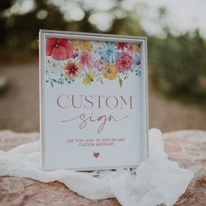 May include: A framed sign with a floral watercolor design at the top. The sign reads "CUSTOM sign" in a cursive font, with the text "USE THIS SIGN TO DISPLAY ANY CUSTOM MESSAGE!" below. A small heart is at the bottom.