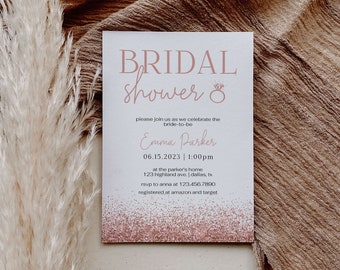 Puede incluir: Una invitación de despedida de soltera blanca con purpurina rosa y texto que dice "BRIDAL SHOWER &" y "Emma Parker". La invitación incluye la fecha y hora de la despedida de soltera, la ubicación y la información de RSVP.