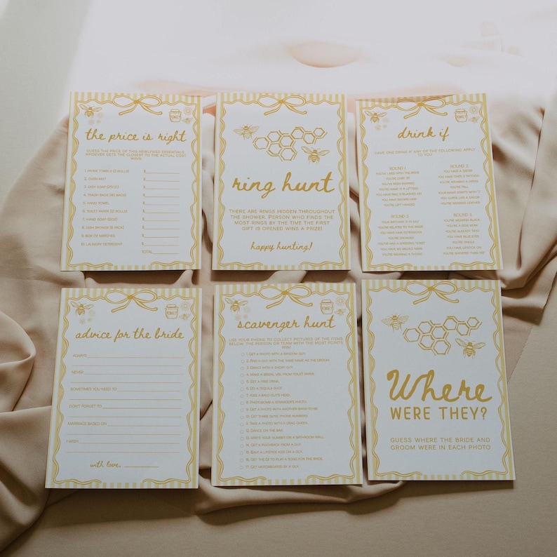 May include: Six rectangular game cards with a yellow and white design. The cards have bee and honeycomb graphics and text such as "the price is right", "ring hunt", "drink if", "advice for the bride", "scavenger hunt", and "where were they?"