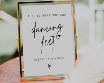 Op de afbeelding: Een gouden lijst met een witte achtergrond en zwarte tekst die "A little treat for your dancing feet. Please take a pair." met een hartje onderaan.