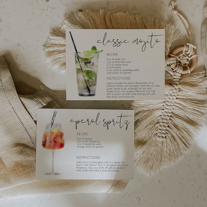 May include: Two recipe cards with watercolor illustrations of cocktails. The first card is for a classic mojito and the second card is for an Aperol spritz. Both cards have the ingredients and instructions for making the cocktails.