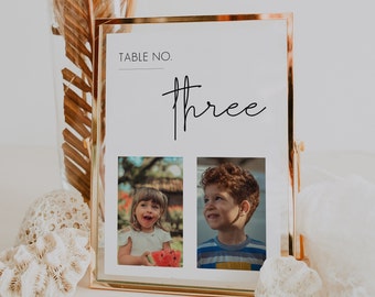 Puede incluir: Un cartel de número de mesa con marco dorado con la palabra "three" escrita en cursiva. El cartel tiene dos ranuras para fotos, una con una niña sosteniendo una sandía y la otra con un niño mirando hacia un lado.