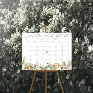 May include: A white calendar with a jungle animal theme for a baby shower. The calendar has the text "guess the arrival date of BABY SOPHIA" at the top and a heart with the text "Due Date" in the centre.