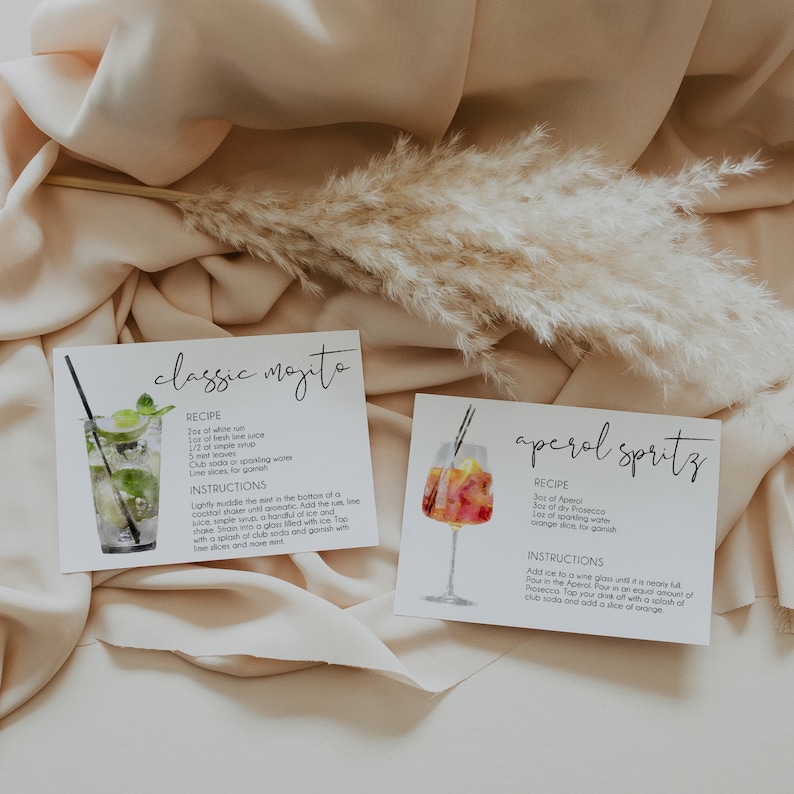 May include: Two recipe cards with watercolor illustrations of cocktails. The first card is for a classic mojito and the second card is for an Aperol spritz. Both cards have the ingredients and instructions for making the cocktails.