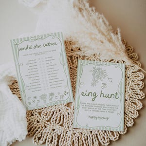 May include: Two light green and white striped cards with text for a bridal shower game. One card says "Would she rather" with a list of choices. The other card says "ring hunt" with instructions. Both cards have floral illustrations.