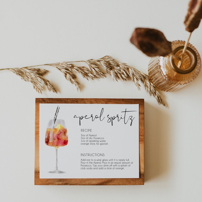 May include: A printable recipe card with a watercolor illustration of an Aperol Spritz cocktail. The card has the title "Aperol Spritz" and includes the recipe and instructions for making the drink.