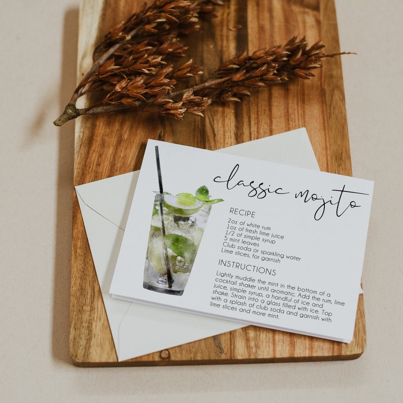 May include: A white card with a watercolor illustration of a classic mojito cocktail. The card includes the recipe for the drink, which includes 2 ounces of white rum, 1 ounce of fresh lime juice, 1/2 ounce of simple syrup, 5 mint leaves, club soda or sparkling water, and lime slices for garnish. The card also includes instructions on how to make the drink.