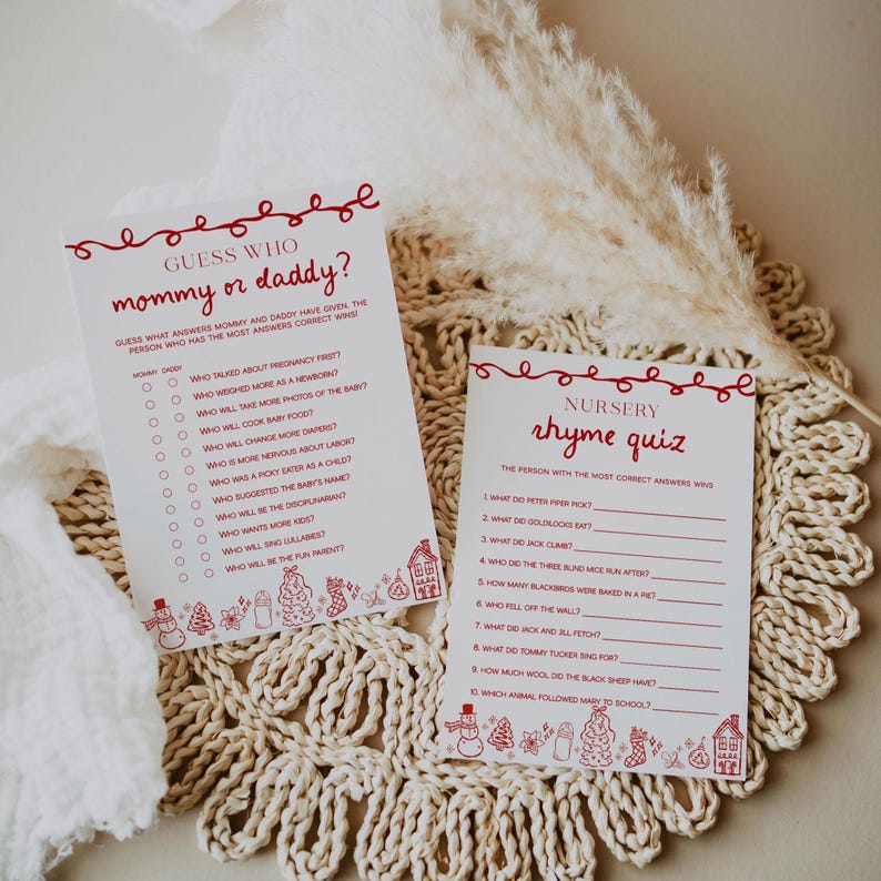 May include: Two white cards with red text and decorative elements. One card reads "Guess Who mommy or daddy?" and the other reads "Nursery rhyme quiz." Both cards are on a woven, beige surface.