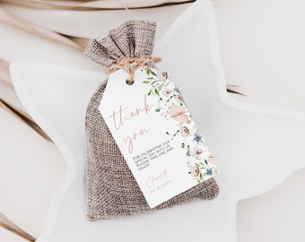 Puede incluir: Una pequeña bolsa de arpillera con una etiqueta blanca atada a ella. La etiqueta tiene un diseño floral y el texto "thank you" en escritura cursiva rosa. El texto debajo dice "For celebrating our special day with us. Please take one and enjoy!" seguido de "Charlotte 07.31.20XX".
