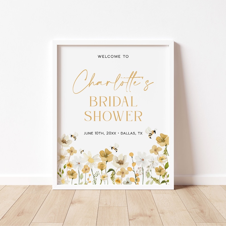 K&ouml;nnte beinhalten: Ein wei&szlig;es Schild mit goldener Schrift, auf dem "Willkommen zu Charlotte's Bridal Shower" steht, darunter das Datum und der Ort. Das Schild ist mit einer Aquarell-Illustration von gelben und wei&szlig;en Blumen und Bienen verziert.