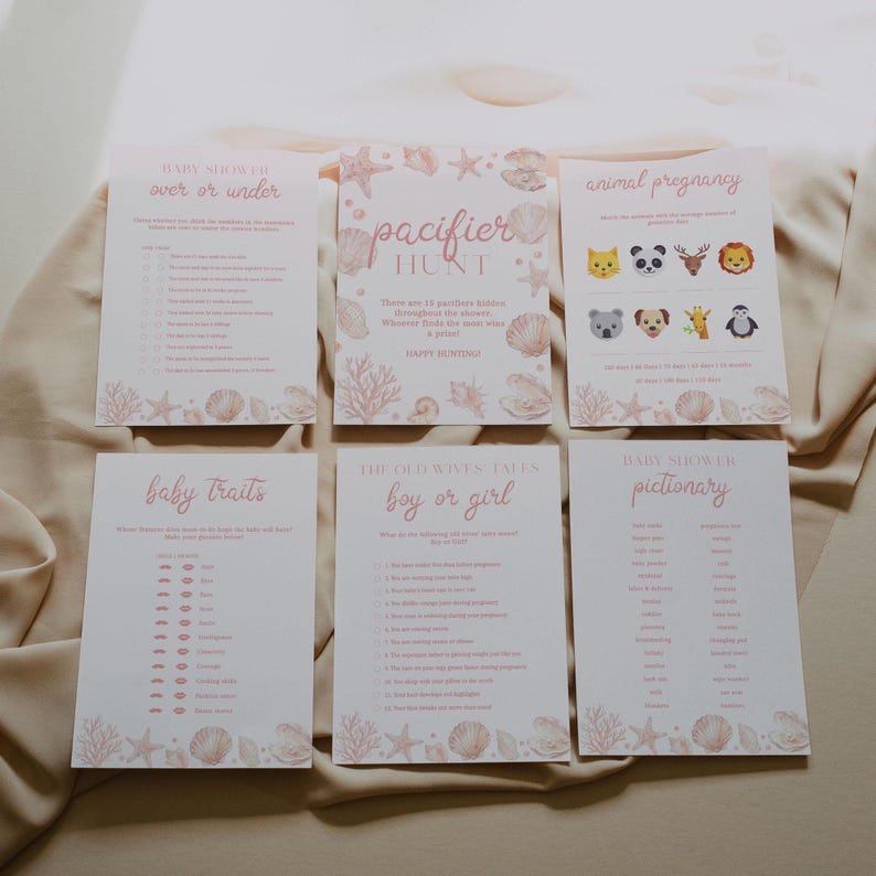 May include: Six rectangular baby shower game cards with a light pink seashell and coral border. The cards feature titles including Baby Shower Over or Under, Pacifier Hunt, Animal Pregnancy, Baby Traits, The Old Wives Tales Boy or Girl, and Pictionary.