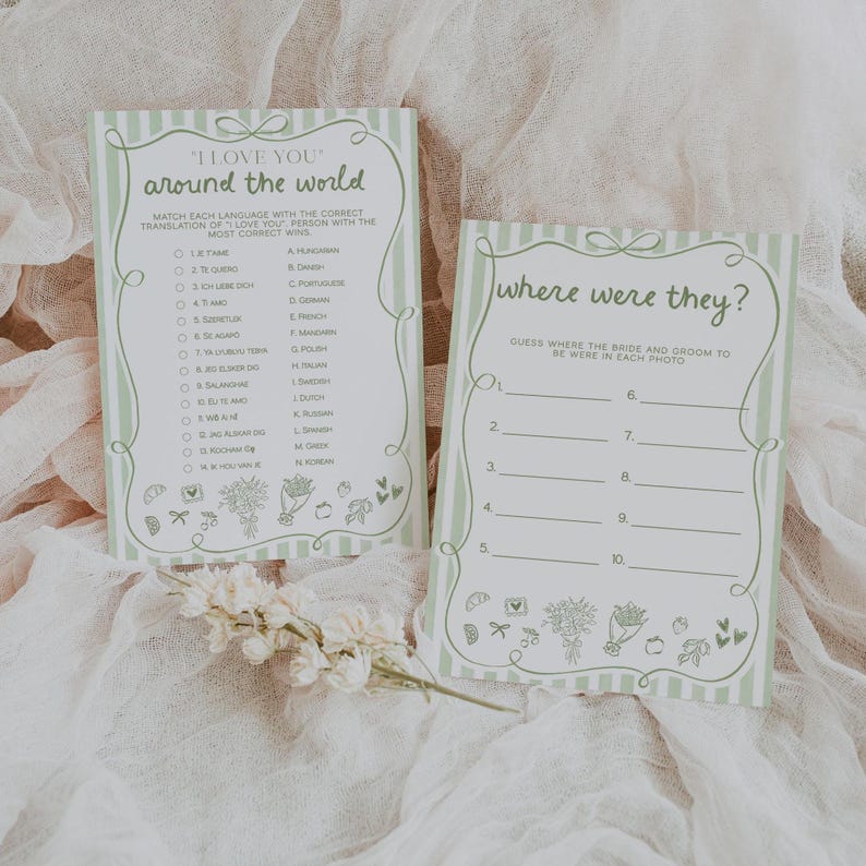 May include: Two light green and white striped game cards with the text "I Love You Around the World" and "Where Were They?". The cards have decorative floral and bow accents. The "I Love You" card has a matching game with language translations.