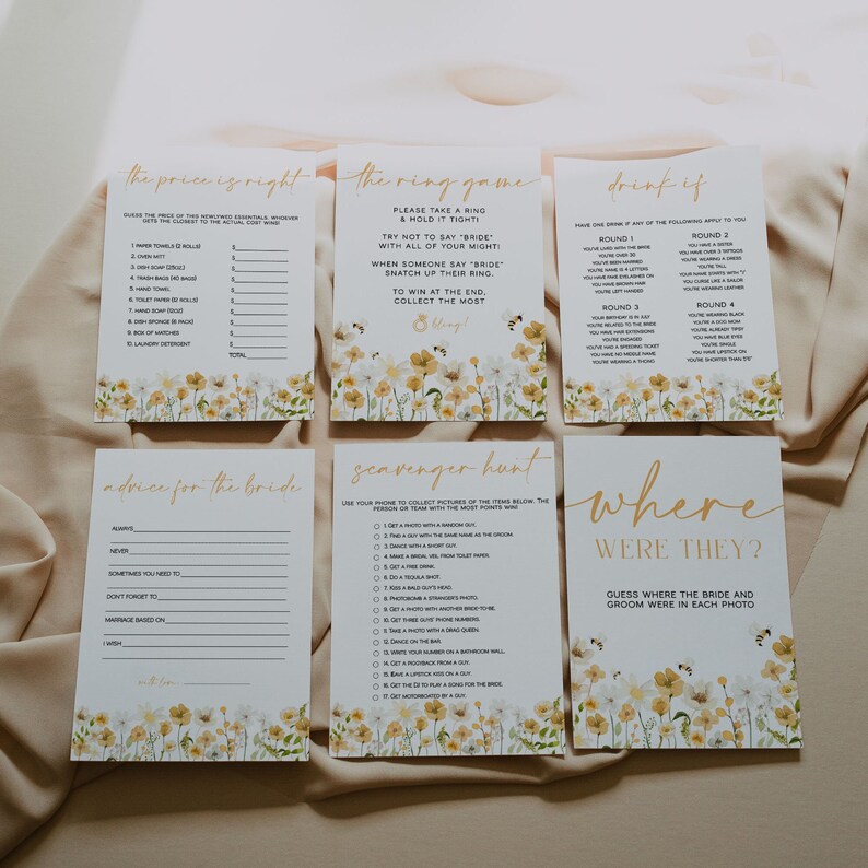May include: A collection of six white cards with gold text and floral accents, designed for a bridal shower. The cards feature various games and activities, including "The Price is Right," "The Ring Game," and "Where Were They?"
