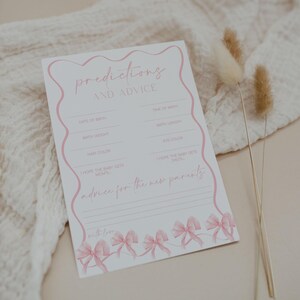 May include: A white baby shower game card with pink text and accents. The card reads "Predictions and Advice" and includes prompts for guests to fill out, such as "Date of Birth" and "Advice for the new parents."