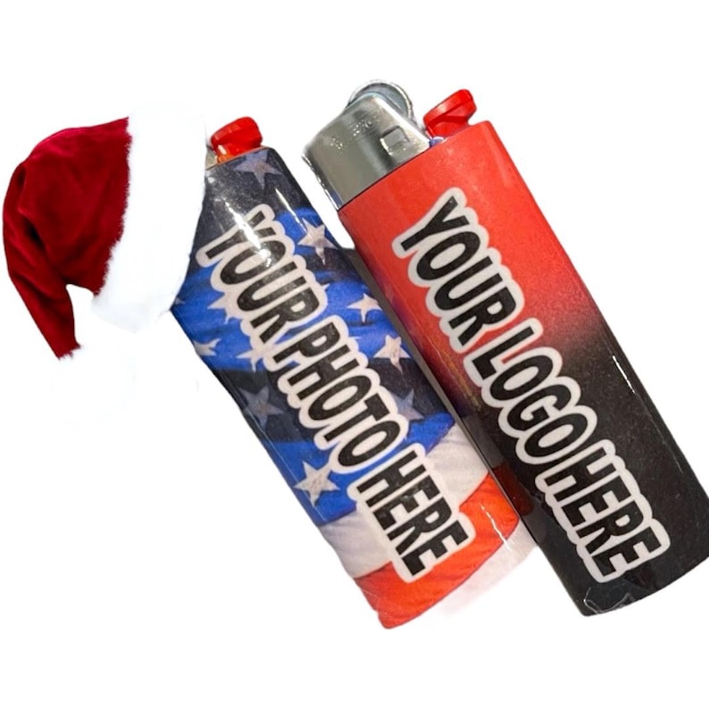 May include: Two custom lighters with text. One lighter features an American flag design with the text "YOUR PHOTO HERE." The other lighter has a red and black gradient with the text "YOUR LOGO HERE." A red Santa hat is in the background.