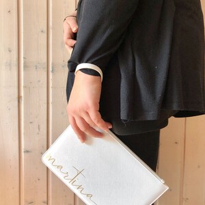 Pode incluir: Clutch branca com uma inscri&ccedil;&atilde;o dourada que diz "martina".