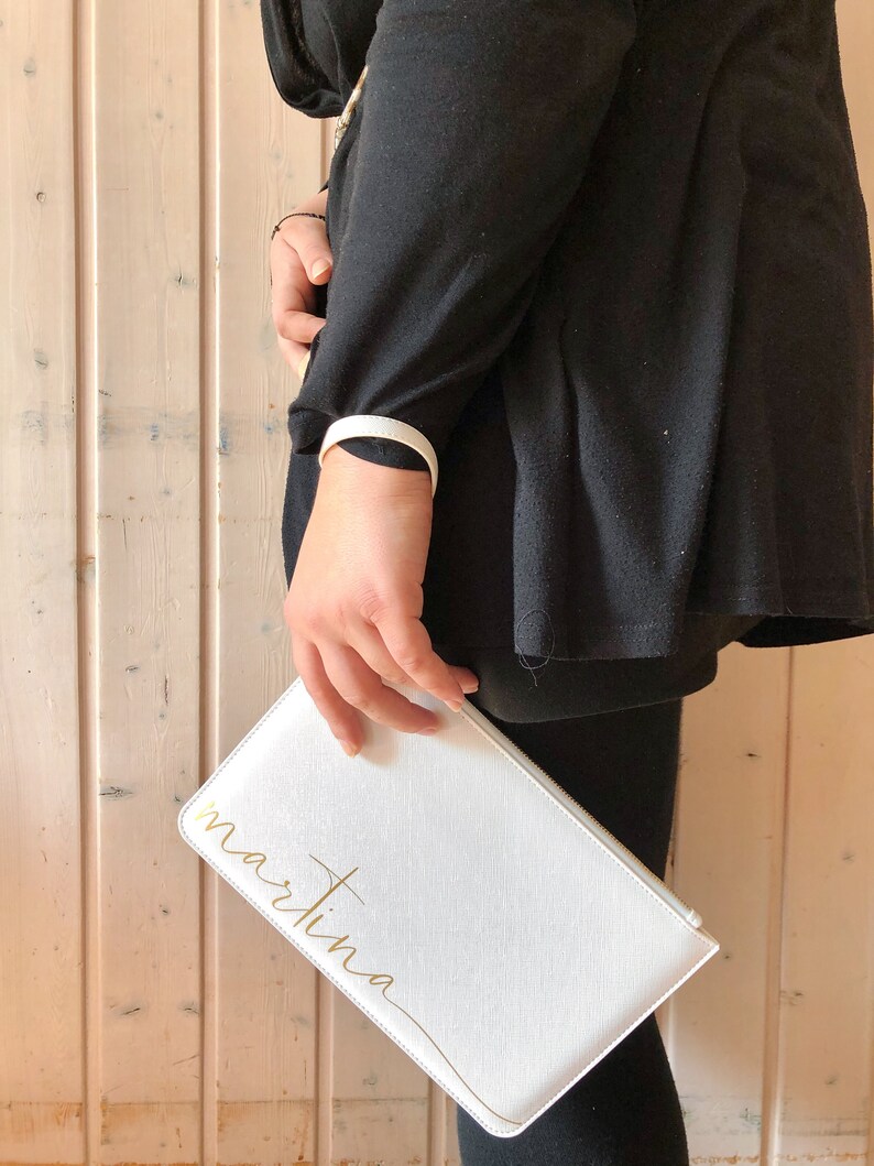 Pode incluir: Clutch branca com uma inscri&ccedil;&atilde;o dourada que diz "martina".