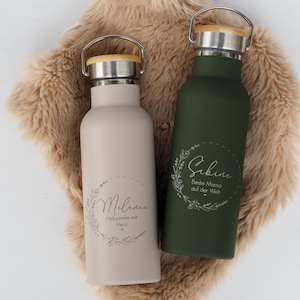 Könnte beinhalten: Zwei Edelstahl-Wasserflaschen mit personalisiertem Text und floralen Designs. Die Flasche links ist beige mit dem Text "Melanie" und "Hab ich im Herzen". Die Flasche rechts ist grün mit dem Text "Sabine" und "Beste Mama auf der Welt".