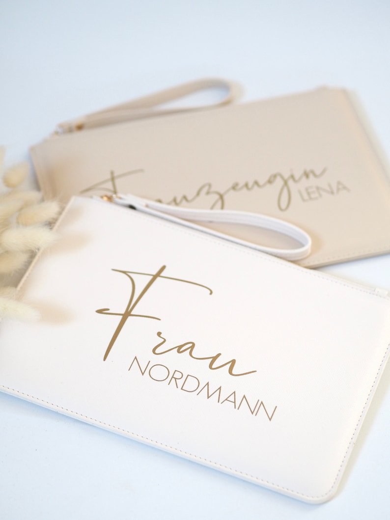 Pode incluir: Duas bolsas de m&atilde;o brancas com letras douradas. Uma bolsa diz "Frau Nordmann" e a outra diz "Trauzeugin Lena".