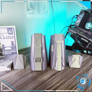 May include: Four 3D printed gray plastic pieces, two tall and two short, with intricate details. The tall pieces have a cylindrical shape with a rounded top and a flat bottom. The short pieces are triangular with a rounded top and a flat bottom. The pieces are arranged on a wooden surface.