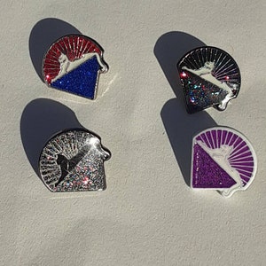 May include: Four enamel pins with a white cat silhouette on a glittery background. The pins are in the shape of a half-circle with a red, black, silver, and purple background.