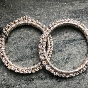 May include: Two silver and gold braided elastic hair ties.