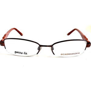 May include: Brown and red petite fit eyeglasses with the brand name BCBGMAXAZRIA printed on the right lens.