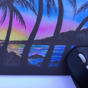 Pode incluir: Tapete de rato com uma cena vibrante de p&ocirc;r do sol com palmeiras em silhueta contra um c&eacute;u colorido. O design inclui uma praia e um oceano, com um rato de computador preto em primeiro plano.