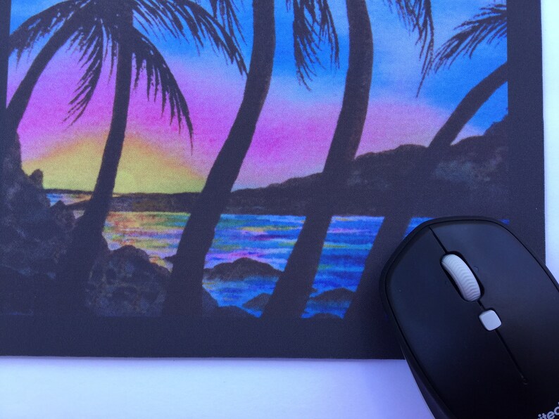 Pode incluir: Tapete de rato com uma cena vibrante de p&ocirc;r do sol com palmeiras em silhueta contra um c&eacute;u colorido. O design inclui uma praia e um oceano, com um rato de computador preto em primeiro plano.
