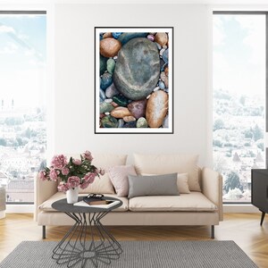 May include: A framed art print featuring a close-up of colorful river rocks. The rocks vary in size and color, with shades of blue, green, brown, and gray. The artwork is displayed in a living room setting with a neutral-toned sofa and a city view.